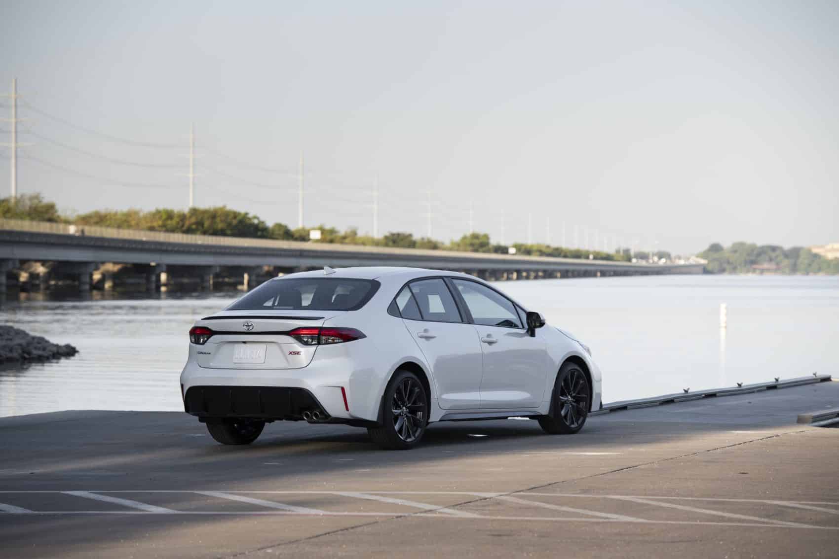 Белый автомобиль Toyota Corolla 2023 года припаркован у воды.