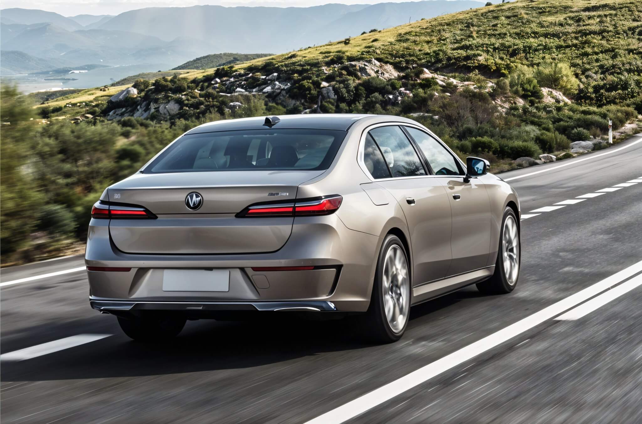 BMW i7: серый электромобиль в движении на трассе с горным пейзажем на фоне.