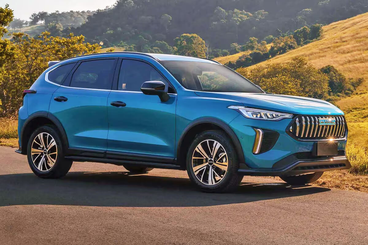 Синий Haval Jolion на дороге с холмами и полями на фоне, в сравнении с Nissan Qashqai.