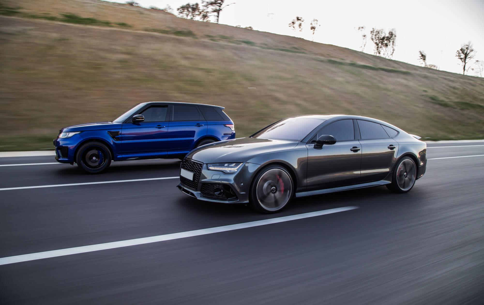 Синий Range Rover и серый Audi в движении на трассе — какие авто выбирают блогеры для стильного контента.