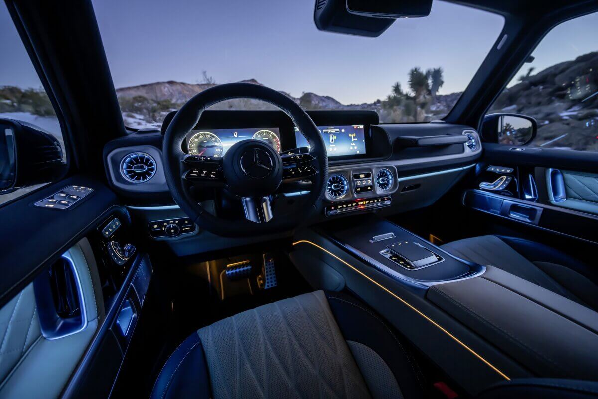 Интерьер Mercedes-Benz G-Class 2025 с современной панелью приборов и элегантной подсветкой, демонстрирующий роскошь и технологичность.