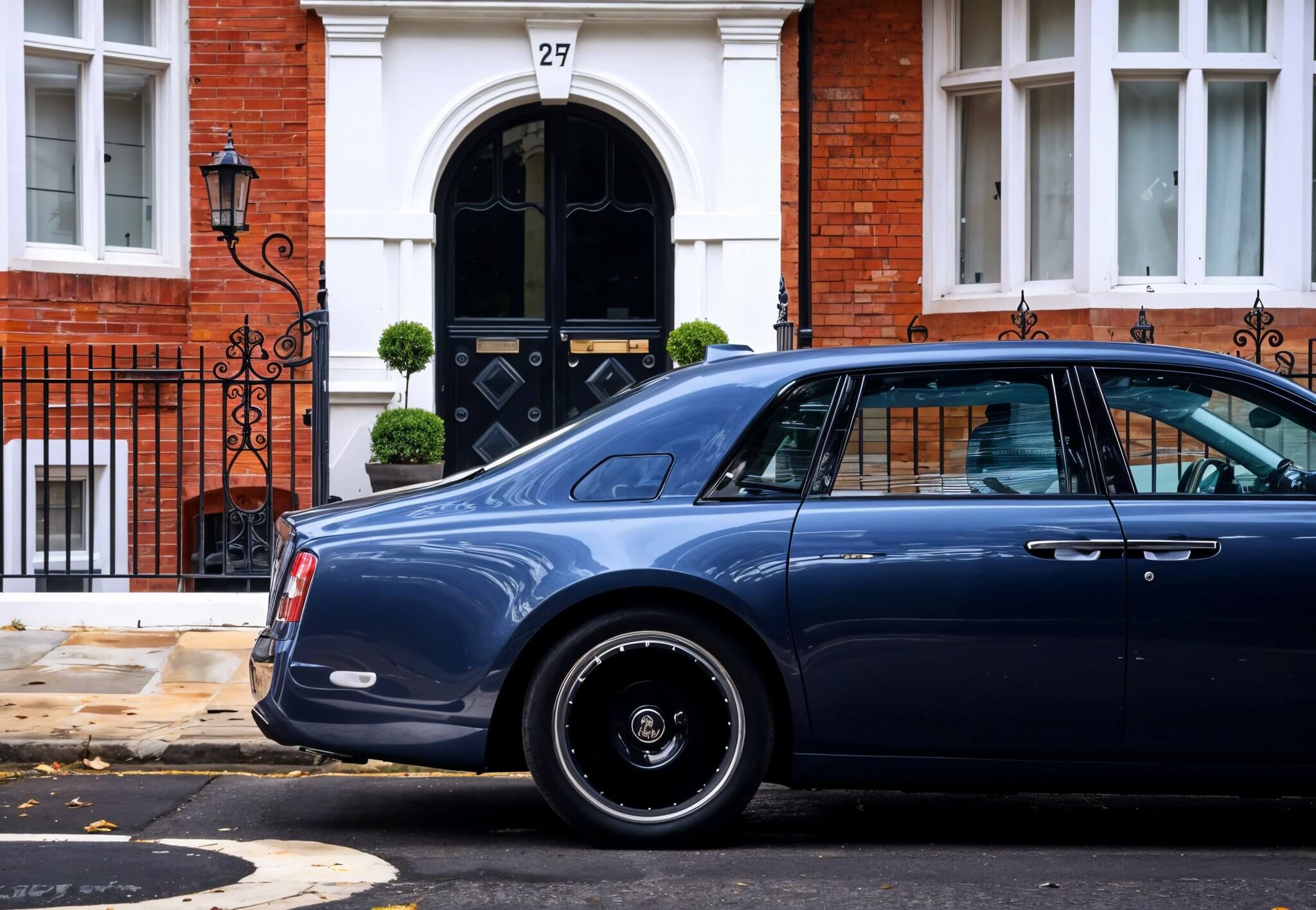 Rolls-Royce Phantom Series II: синий роскошный седан припаркован у кирпичного особняка с черной дверью.